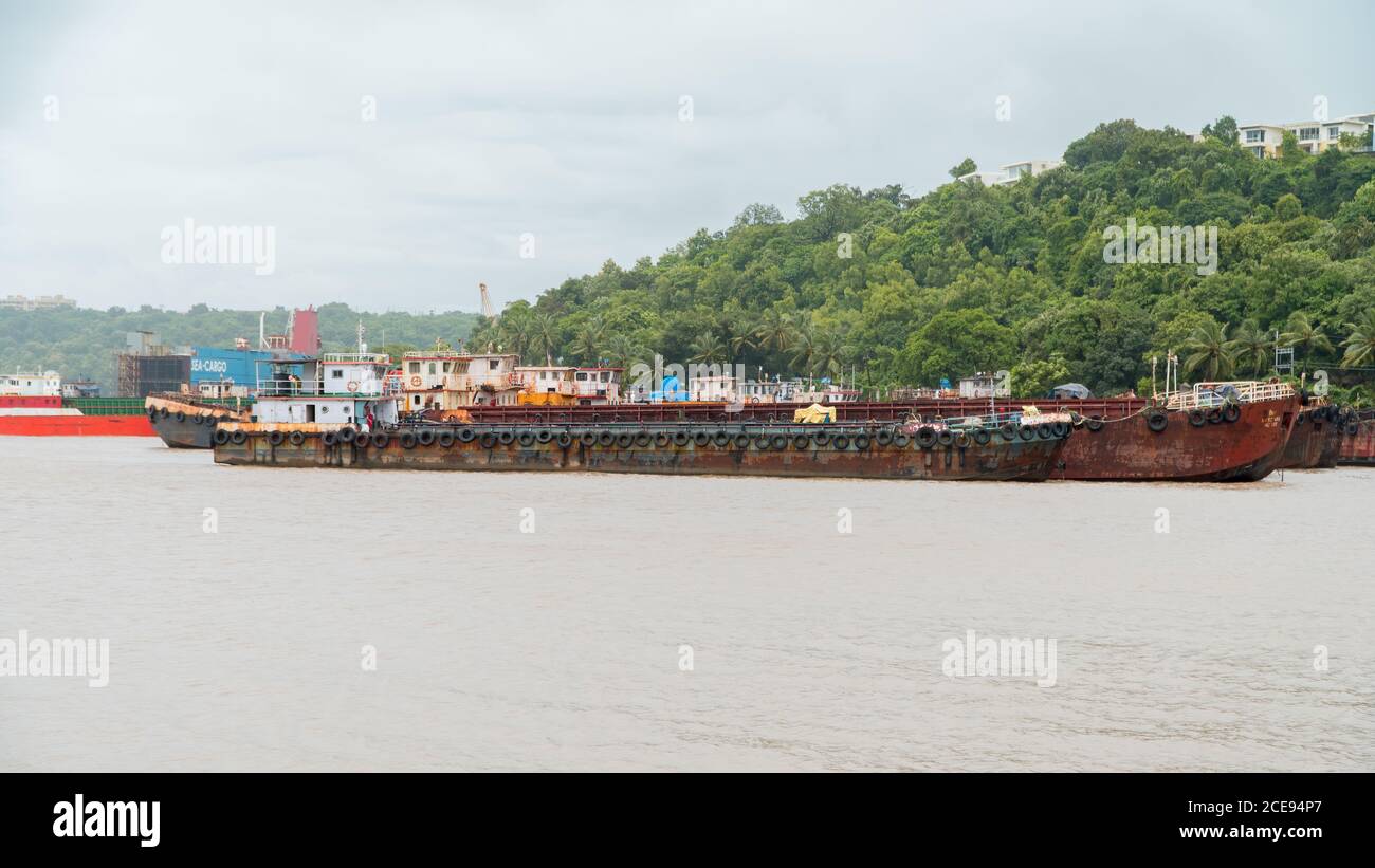 Alcune vecchie chiatte arrugginite sono a ormeggio in un porto di Goa, India. Foto Stock