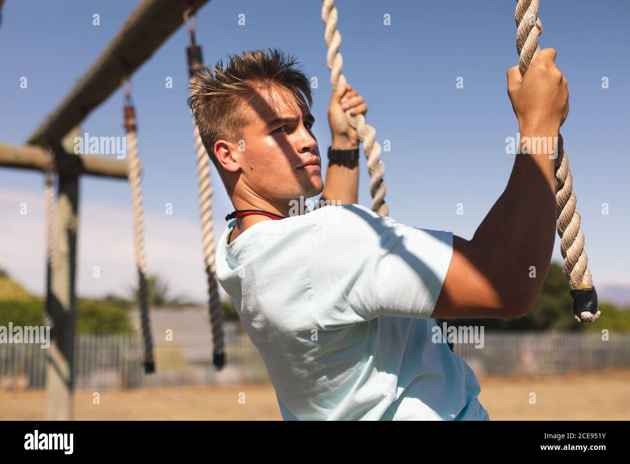 Allenatore di fitness maschile che tiene corde e appeso a uno stivale campo Foto Stock