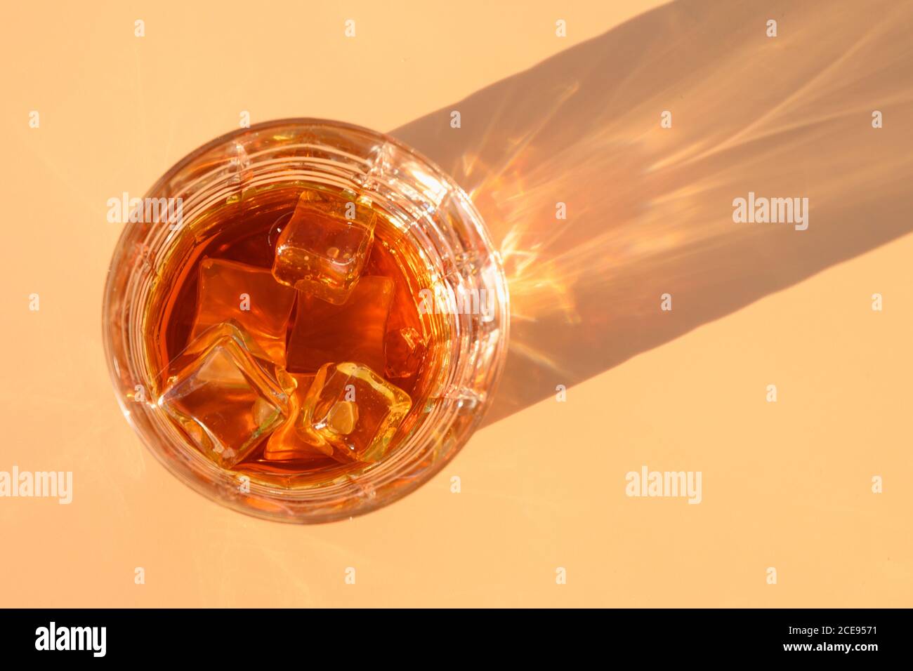 Bicchiere di whisky freddo su sfondo beige con ombra soleggiata. Foto Stock