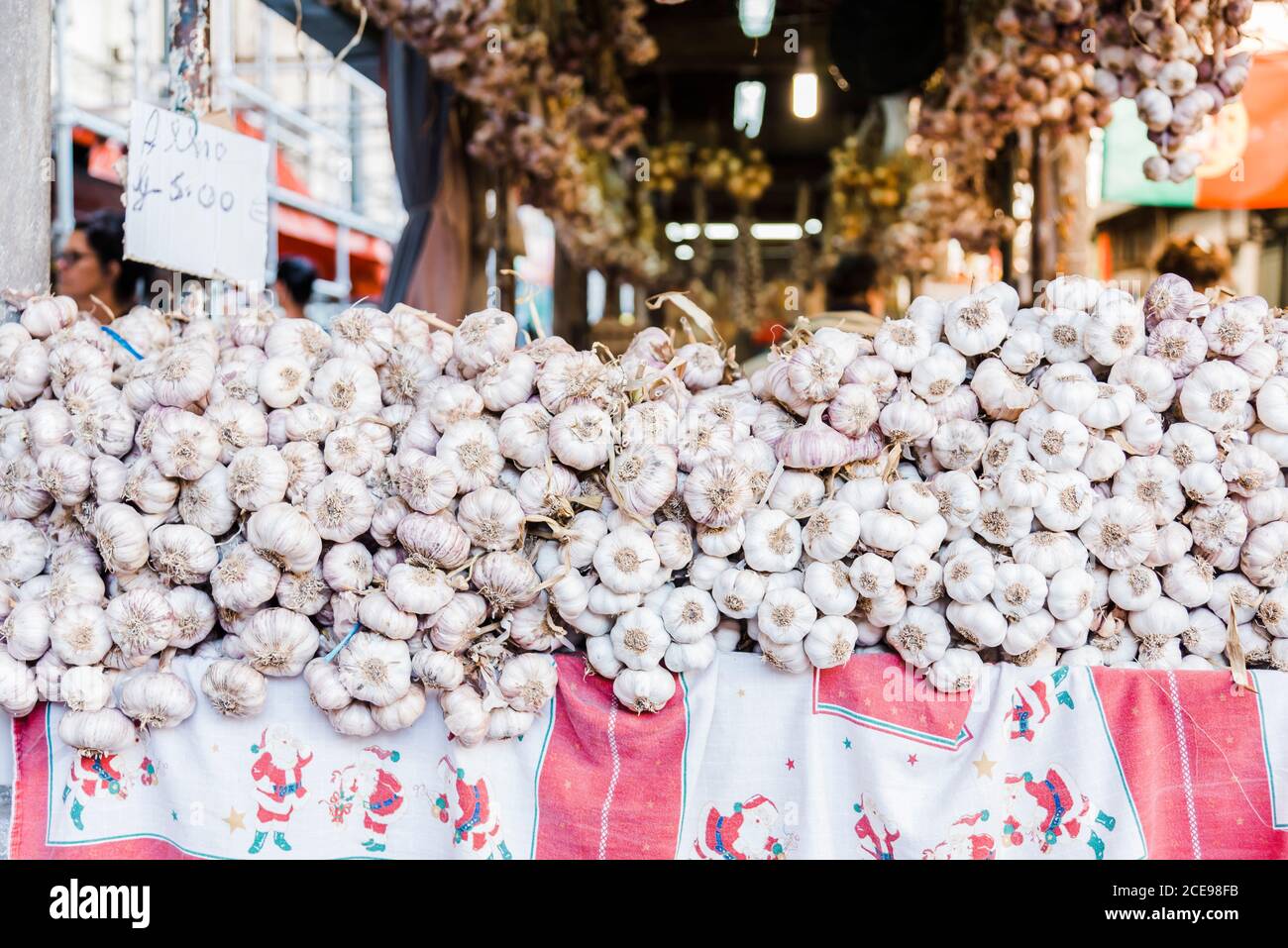 Aglio fresco accatastato su un tavolo all'interno di un mercato. Foto Stock