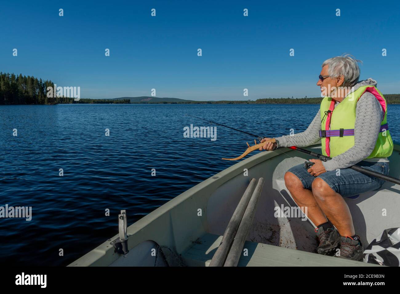 Donne in pensione in una piccola barca su un lago di pesca con vecchie attrezzature, cielo blu e orizzonte sullo sfondo, foto da Vasternorrland Svezia. Foto Stock