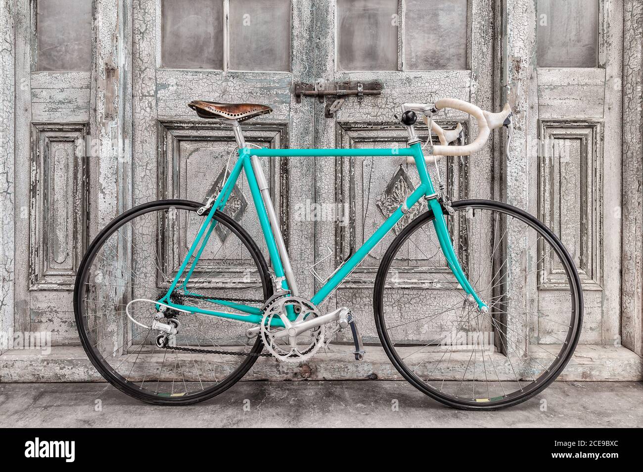 Bicicletta da corsa blu chiaro vintage anni '70 con sella in pelle davanti  alle vecchie porte in legno bianco e nero Foto stock - Alamy