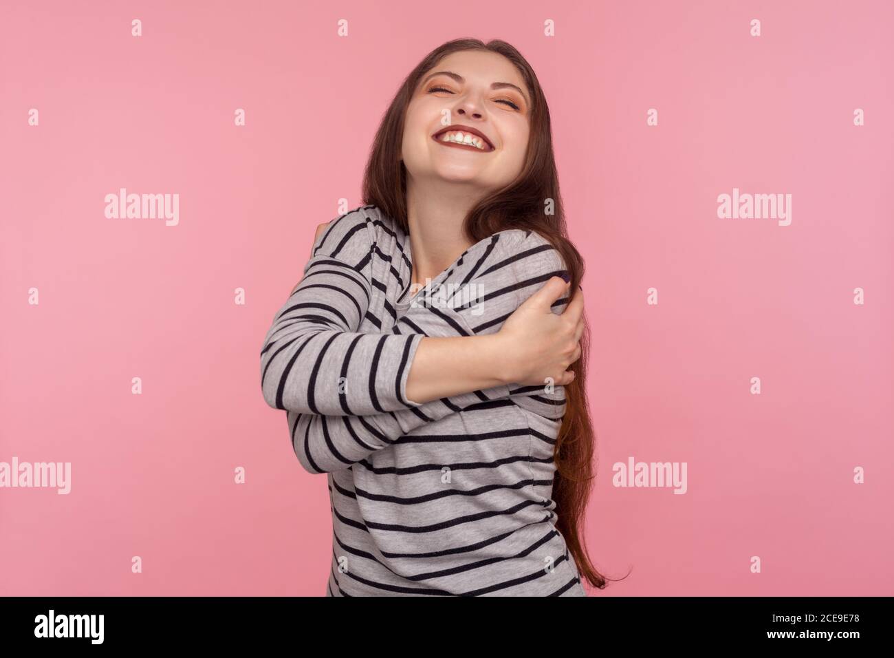 Mi voglio bene! Ritratto di bella donna egoista in felpa a righe che si abbraccia, essendo orgoglioso e autosoddisfatto narcisistico persona con p Foto Stock