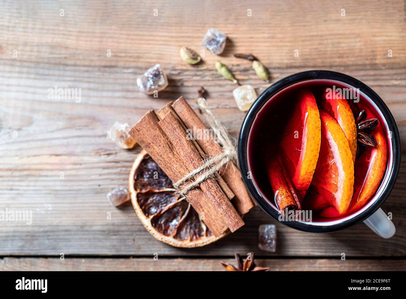 Vino rosso bollito natalizio con spezie e frutta su un tavolo rustico in legno. Foto Stock