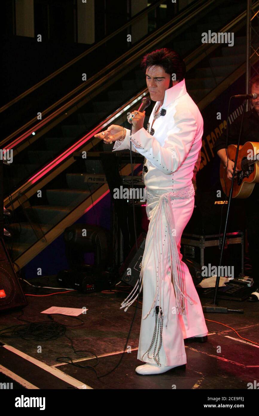 Glasgow Prestwick Airport Ayrshire nel Regno Unito è l'unico luogo vistato da 'The King of Rock & Roll Elvis Preseley. Sul servizio natonale Sergent Presley è stato accolto dai tifosi urlanti il 3 marzo 1960 dopo che il suo aereo si è fermato a rifornirsi : Foto una festa atf Glasgow Prestwick Airport come l'aeroporto si riconfigura come 'pure Dead Brilliant' l'aeroporto era stato recentemente rilevato da Infratil Limited, una società di investimenti in infrastrutture con sede in Nuova Zelanda. Elvis Presley ( aka Gordon Hendricks vincitore di stelle ITV ai loro occhi 2005 ) ha intrattenuto lo staff e i clienti dell'aeroporto Foto Stock