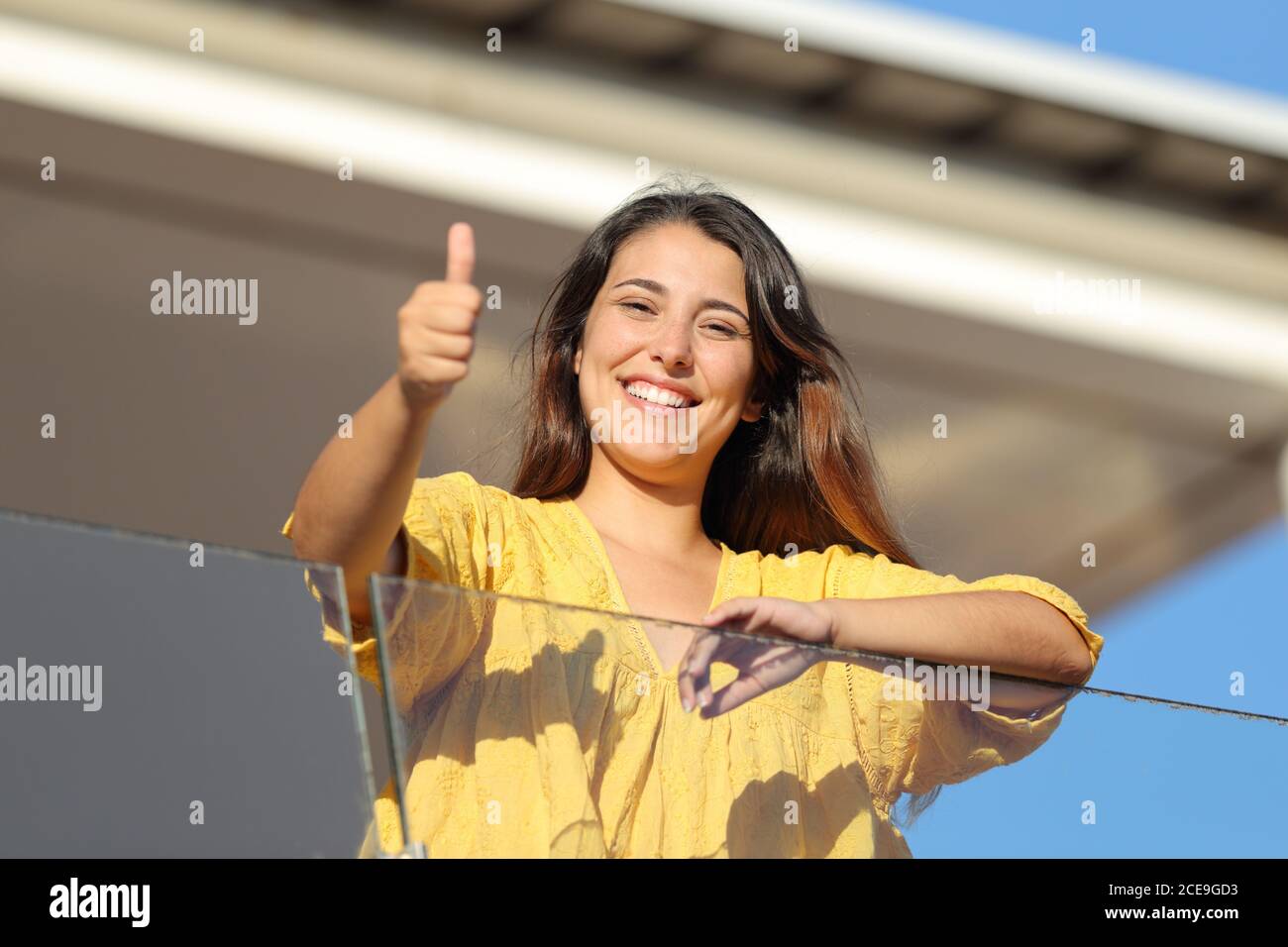 Felice affittuatore appartamento con thums in su ti guarda dentro un balcone una giornata di sole Foto Stock