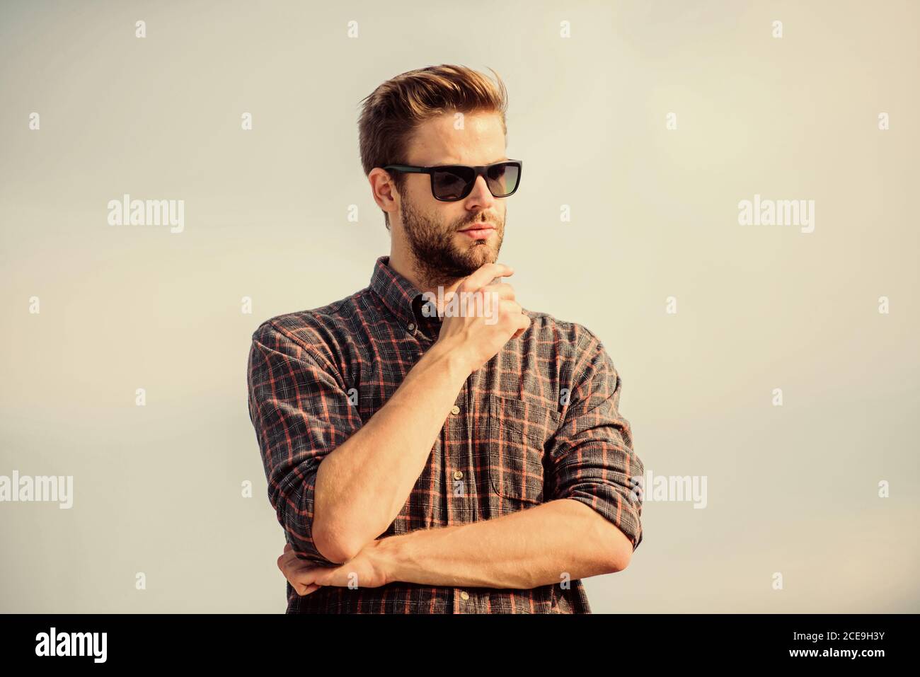 Protezione ultravioletta concetto. Visione perfetta. Vedere chiaro. Bel ragazzo di indossare occhiali da sole. Hipster uomo nel quartiere alla moda di occhiali da sole. Occhiali da sole alla moda. Uomo modello di occhiali all'aperto il cielo blu sullo sfondo. Foto Stock