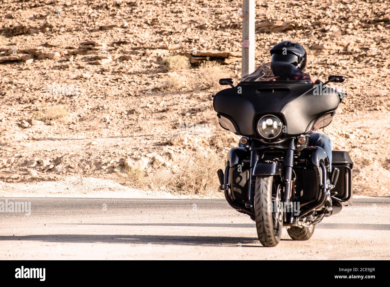 Un'immagine di un ragazzo che indossa un casco ama guidare un grande veicolo a motore nero. Foto Stock