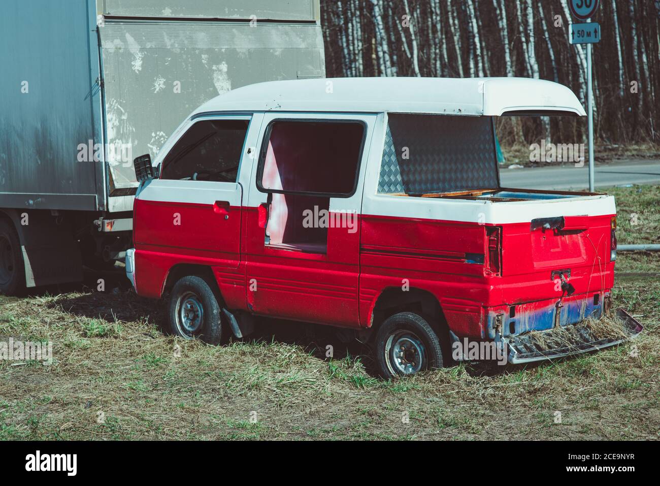 Vecchio arrugginito, abbandonato rosso e bianco relitto del bus in arido paesaggio forestale con le betulle Foto Stock