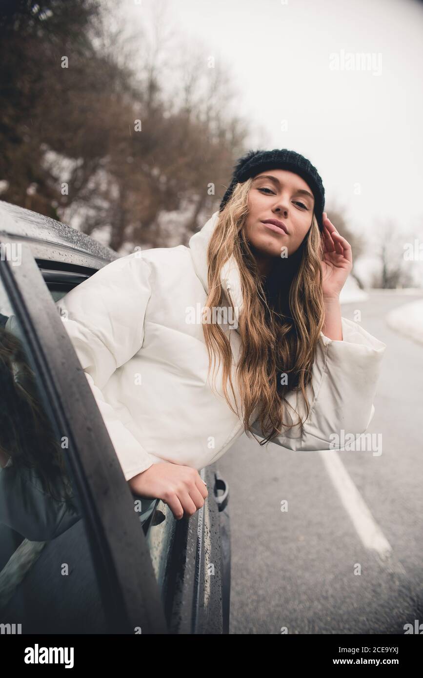 Giovane donna con capelli ricci e cappello divertente sorridendo da auto  nera e guardando la macchina fotografica Foto stock - Alamy
