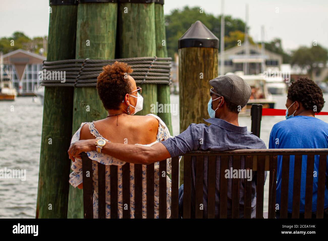 Annapolis, MD 08/21/2020: Una famiglia afroamericana è seduta su una panchina ad Annapolis Marina, guardando le barche che passano. L'uomo mette il braccio sopra Foto Stock