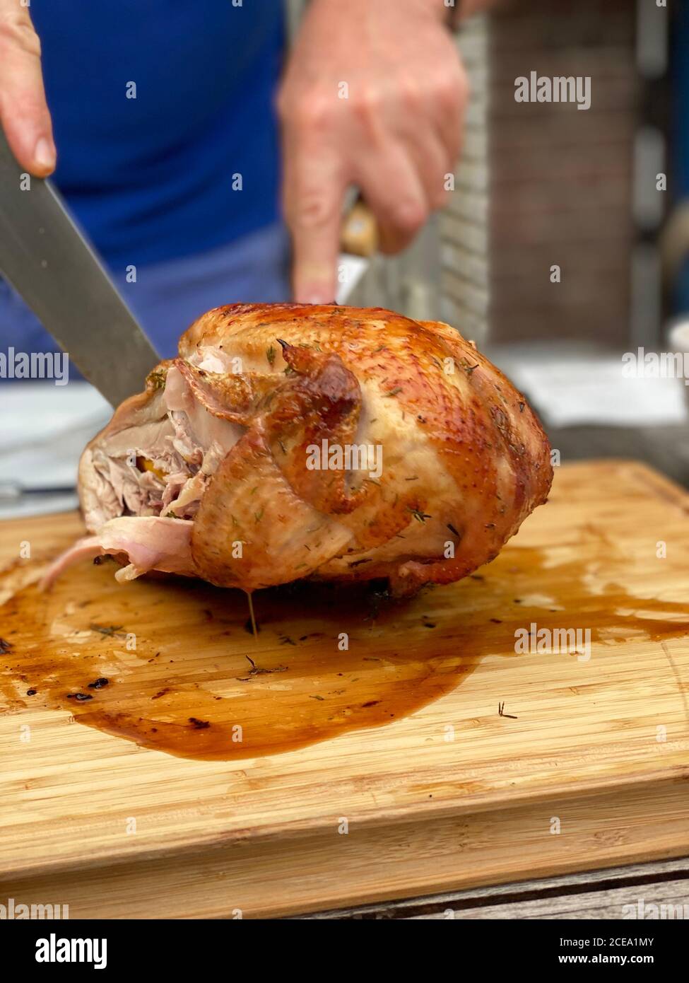 Uomo che taglia il pollo arrosto sul tavolo all'aperto Foto Stock