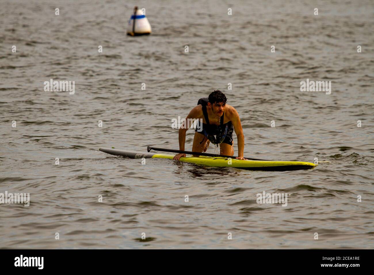 Annapolis, MD 08/21/2020: Un giovane kayak inesperto sta cercando di risalire al suo stand up kayak dopo aver perso il suo equilibrio e cadendo in wat Foto Stock