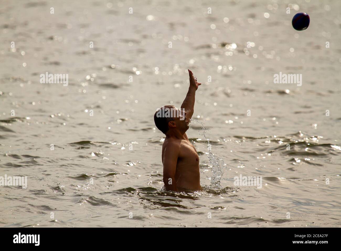 Rock Hall, MD 08/22/2020: Un giovane caucasico sta giocando una partita a palla nella baia di Chesapeake. Sta saltando per raggiungere la palla e catturarla. È un atleta Foto Stock