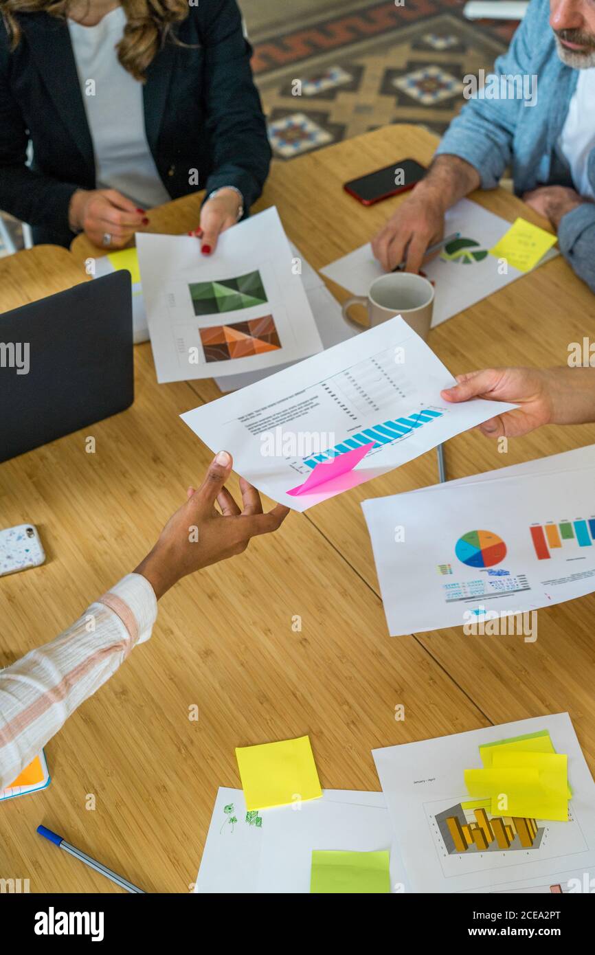 Vista di ritaglio dall'alto del gruppo di lavoratori seduti a. tavolo per riunioni e discussione di schemi e diagrammi in ufficio Foto Stock