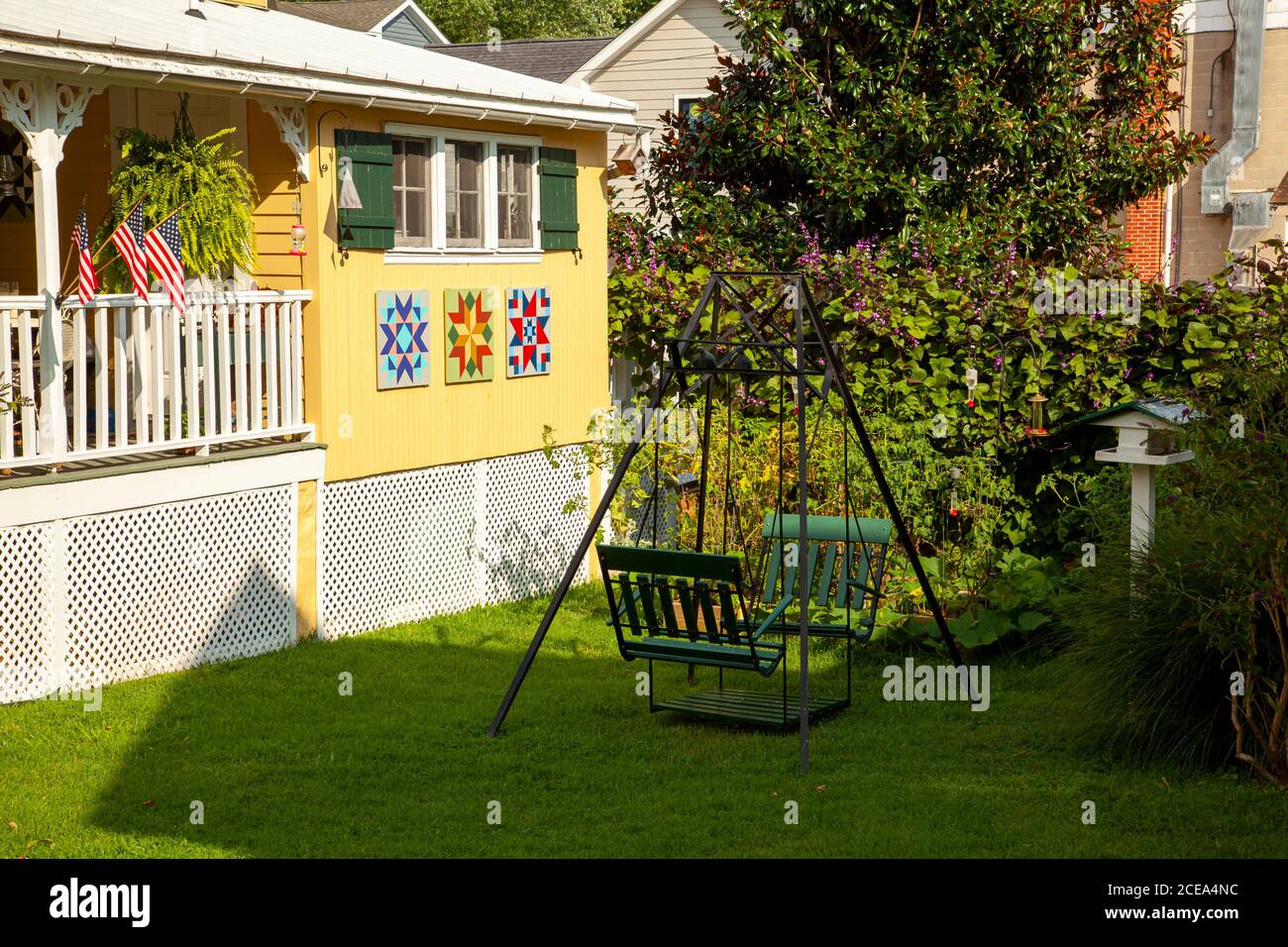 Chesapeake City, MD, USA 08/25/2020: Un'oscillazione verde, in metallo vintage giardino sul cortile anteriore di una tradizionale casa americana di vecchio stile con navette in legno Foto Stock