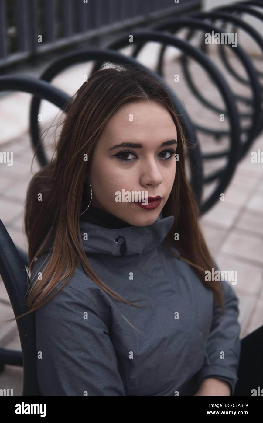 Donna di charme in cappotto e leggini seduti vicino al parcheggio per biciclette Foto Stock