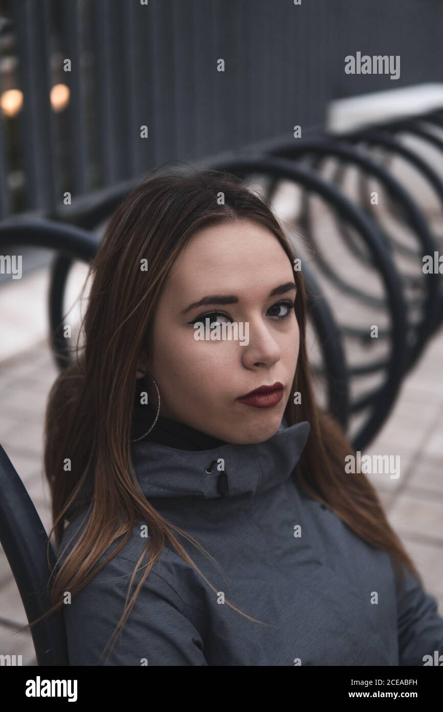 Donna di charme in cappotto e leggini seduti vicino al parcheggio per biciclette Foto Stock