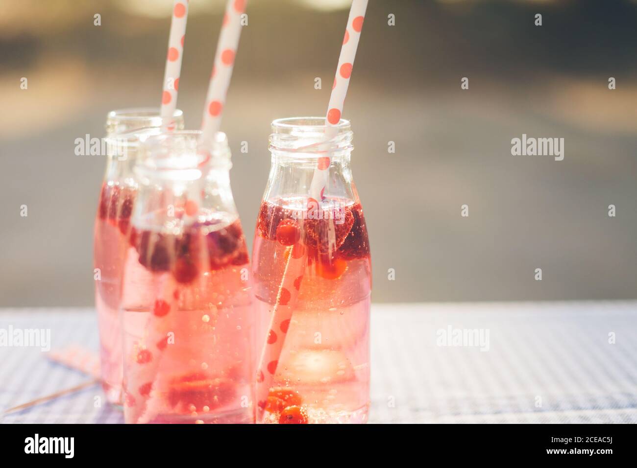 Bottigliette con bevande a base di frutta rossa e tubi in plastica tabella su sfondo sfocato Foto Stock