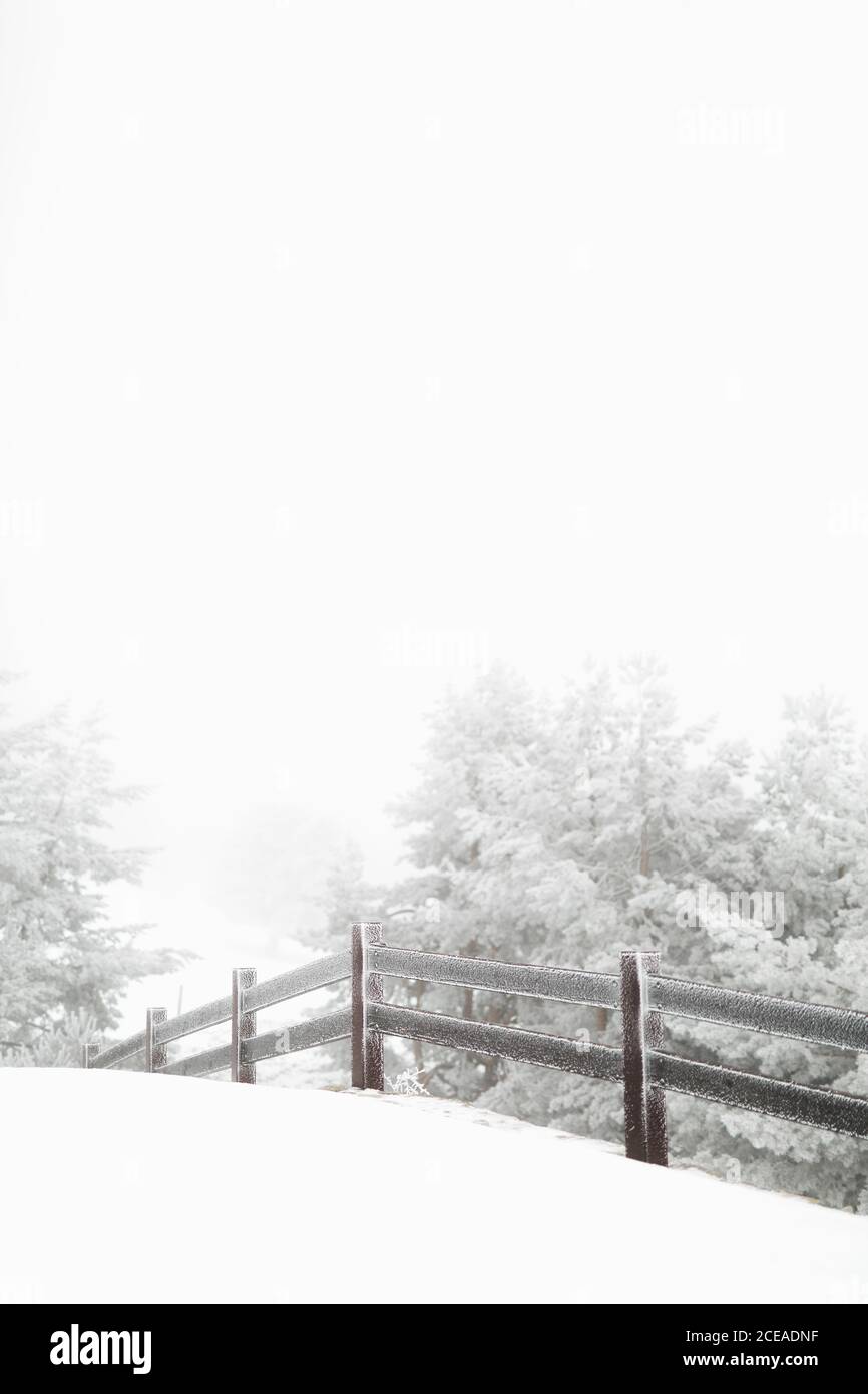 Recinzione di legno coperta di neve in piedi in magnifica campagna su bella giornata invernale Foto Stock