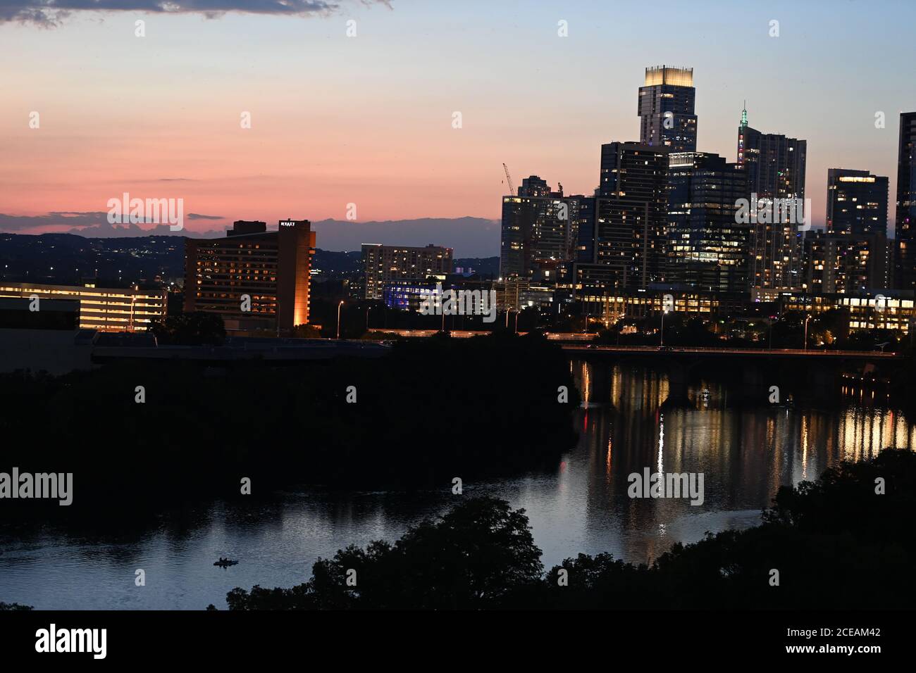 Austin, TX 18 agosto 2020: La parte meridionale dello skyline della città di Austin che si riflette nelle acque del lago Lady Bird guardando verso ovest al tramonto a metà agosto. La nuova costruzione continua a crescere nel centro di Austin nonostante il rallentamento economico nazionale. Foto Stock