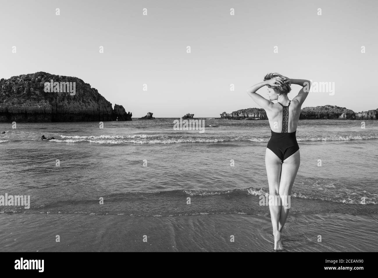 vista posteriore in bianco e nero della femmina in piedi vicino mare Foto Stock