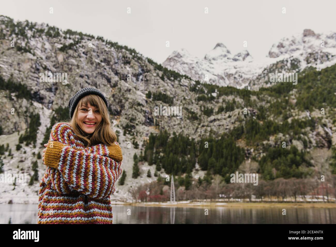 Attraente ragazza in maglione e hat con due mani incrociate vicino colle su sfondo sfocato nei Pirenei Foto Stock