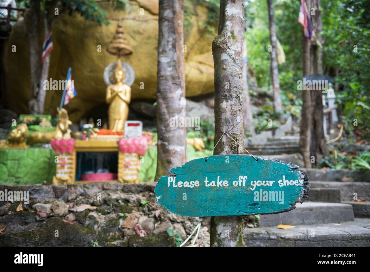 Si prega di togliere le scarpe con il cartello in legno presso la statua  dorata del Buddha in Thailandia Foto stock - Alamy