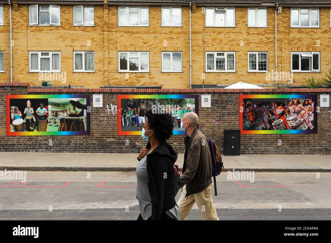 Londra, Gran Bretagna. 31 Agosto 2020. La gente passa accanto ai manifesti del Carnevale di Notting Hill nella zona di Notting Hill a Londra, Gran Bretagna, il 31 agosto 2020. Il Notting Hill Carnival, un evento annuale con sistemi audio e bande di sfilate che si è svolto sulle strade di Londra ovest dalla metà degli anni '60, si è tenuto praticamente dal 29 al 31 agosto, mentre la Gran Bretagna sta lottando per controllare la diffusione del coronavirus. Credit: Tim Ireland/Xinhua/Alamy Live News Foto Stock