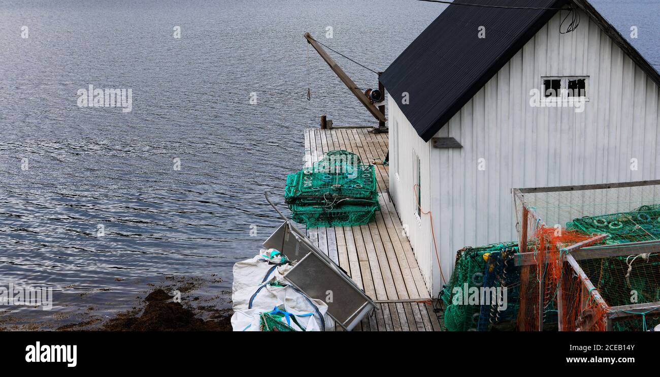 Vecchio capannone bianco di legno di pescatore con reti di granchio alla costa del mare, Norvegia Foto Stock