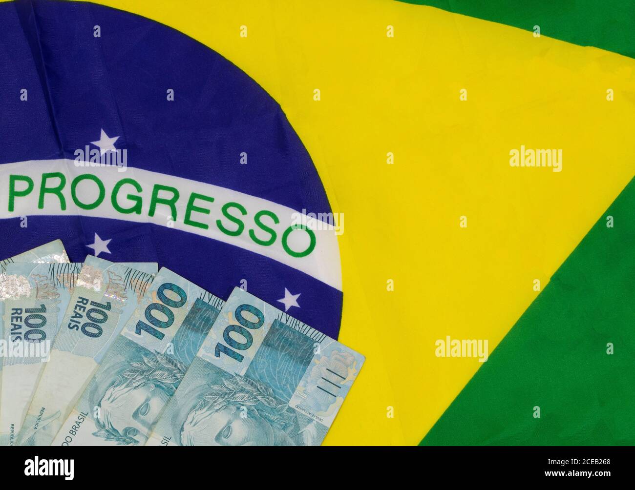 Bandiera brasiliana sventolante con denaro brasiliano. Immagine concettuale. Foto Stock
