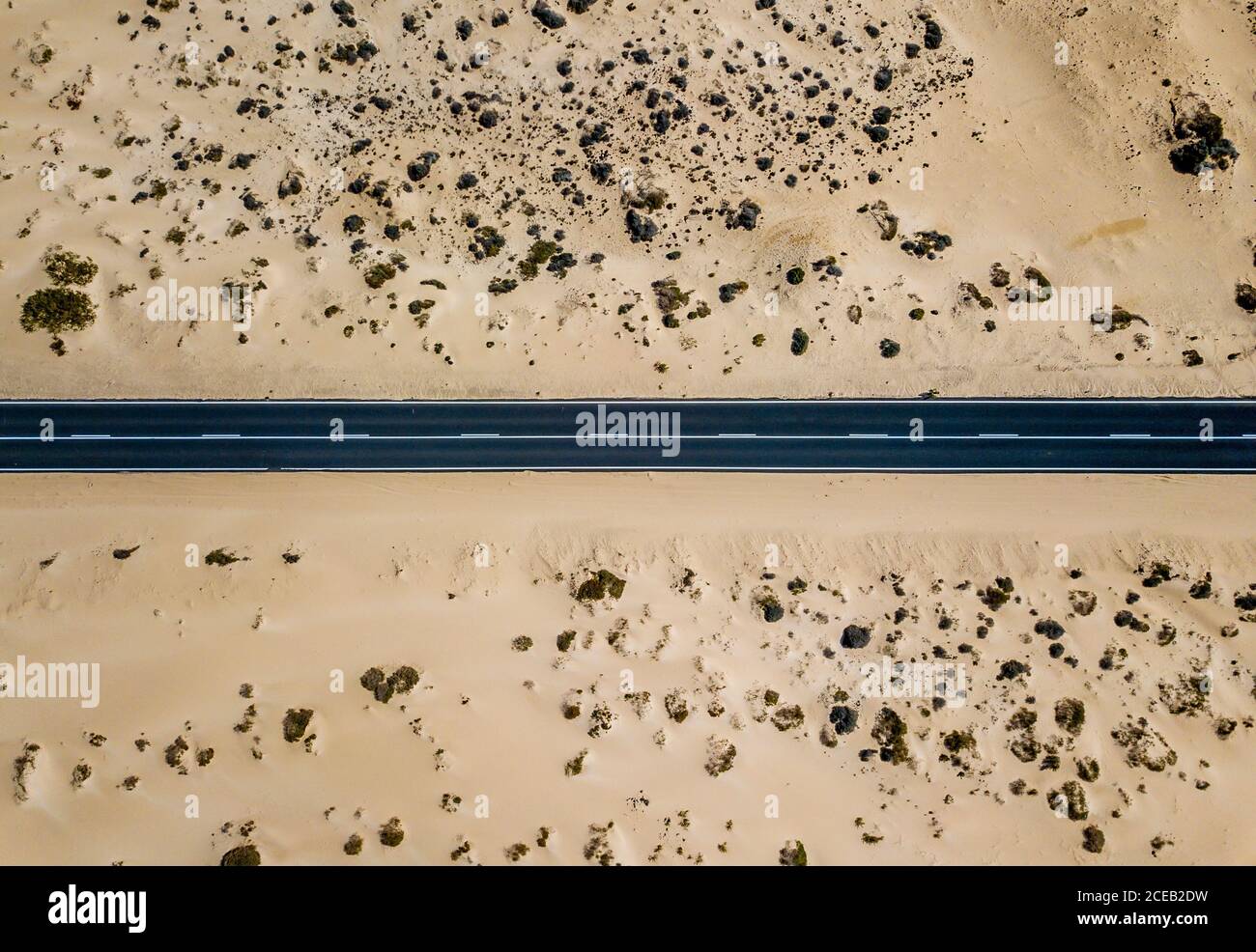 Drone vista dall alto della linea retta di strada lastricata in dry terreno sabbioso del deserto, Spagna Foto Stock