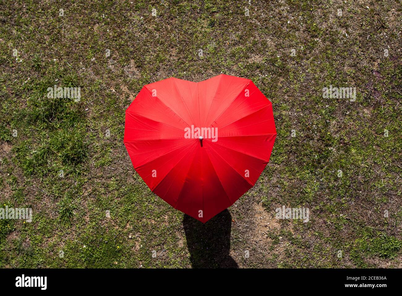 Da sopra persona irriconoscibile che si trova sotto un ombrello rosso a forma di cuore. Foto Stock