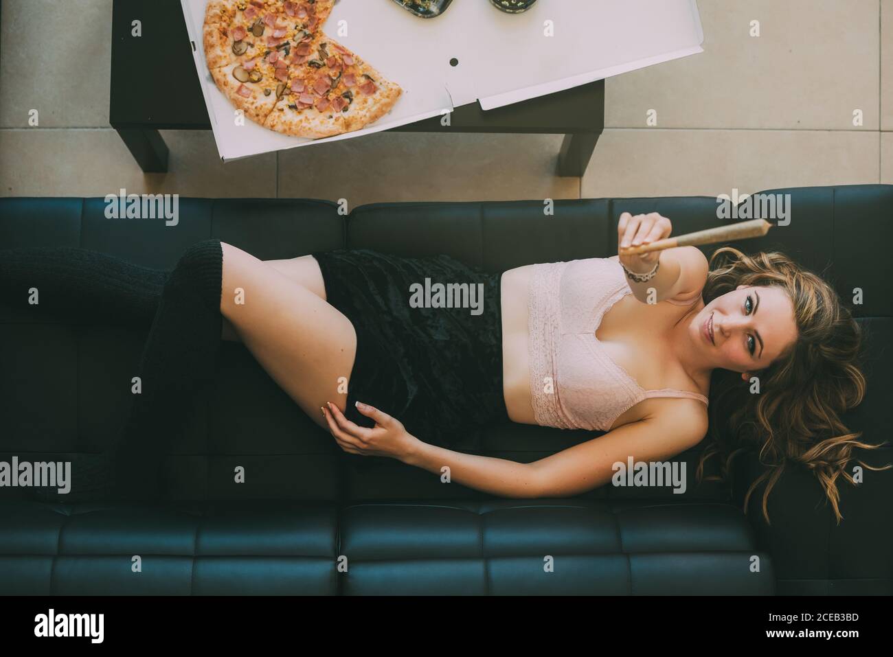 Donna sdraiata sul divano con giunto marijuana Foto Stock