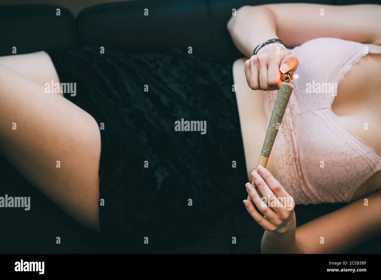 Donna sdraiata sul divano con giunto marijuana Foto Stock