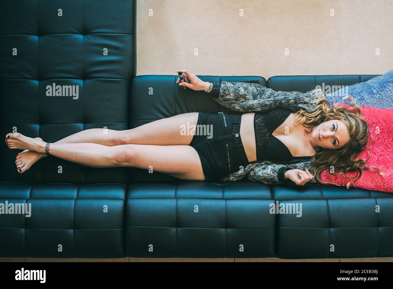 Donna sdraiata sul divano con vetro di cannabis smussato Foto Stock