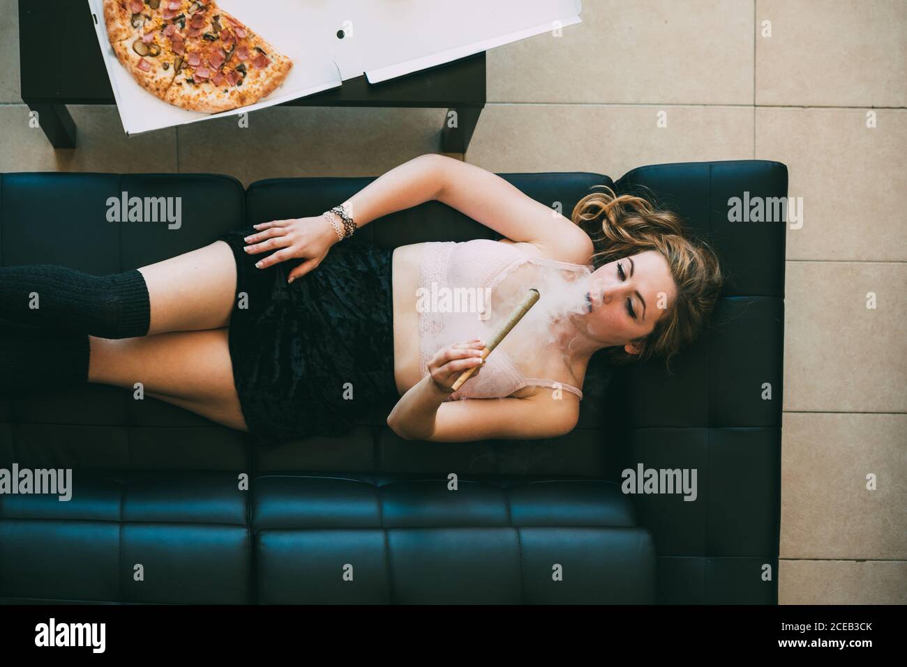 Donna sdraiata sul divano con giunto marijuana Foto Stock