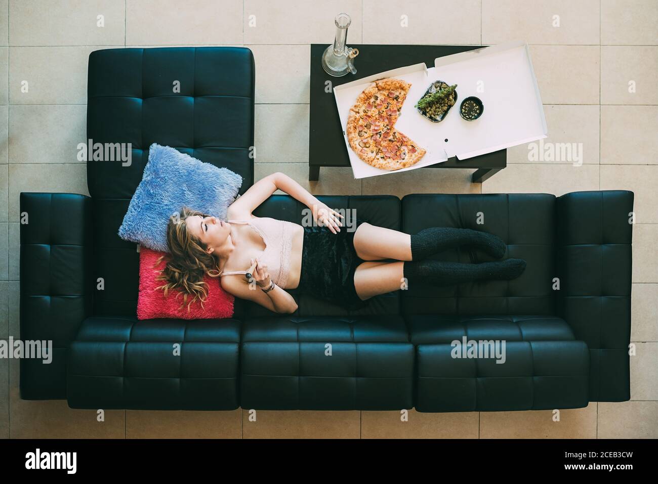 Donna sdraiata sul divano con giunto marijuana Foto Stock