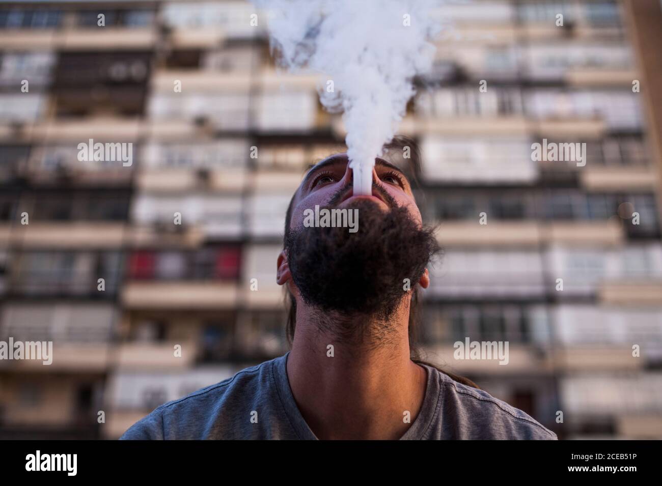 Giovane e caucasico uomo Rastafariano fumare e esporre fumo e. cerca Foto Stock