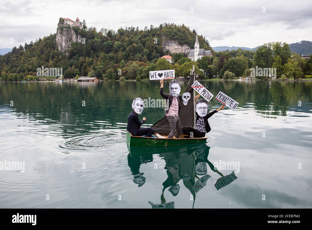 Un gruppo di manifestanti che indossano maschere di carta mostranti i volti del primo ministro sloveno Janez Jansa, del primo ministro ungherese, Viktor Orban e del presidente serbo, Aleksandar Vucic ROW una piccola barca a vela sul lago Bled che protestava contro la loro politica e l'ascesa del fascismo in Europa. La protesta si è svolta accanto al 15° forum strategico di Bled, dove il primo ministro sloveno Janez Jansa ha ha ospitato il primo ministro ungherese Viktor Orban e il presidente serbo Aleksandar Vucic, Oltre ai primi ministri della Repubblica ceca, della Bulgaria, della Polonia, della Croazia e di altri paesi. Foto Stock