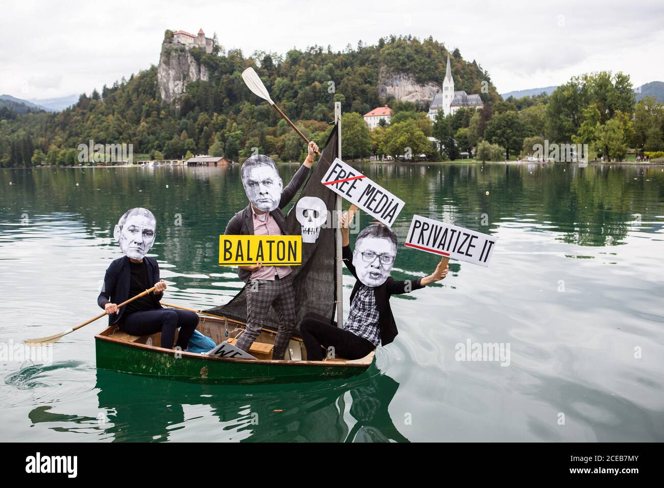 Un gruppo di manifestanti che indossano maschere di carta mostranti i volti del primo ministro sloveno Janez Jansa, del primo ministro ungherese, Viktor Orban e del presidente serbo, Aleksandar Vucic ROW una piccola barca a vela sul lago Bled che protestava contro la loro politica e l'ascesa del fascismo in Europa. La protesta si è svolta accanto al 15° forum strategico di Bled, dove il primo ministro sloveno Janez Jansa ha ha ospitato il primo ministro ungherese Viktor Orban e il presidente serbo Aleksandar Vucic, Oltre ai primi ministri della Repubblica ceca, della Bulgaria, della Polonia, della Croazia e di altri paesi. Foto Stock