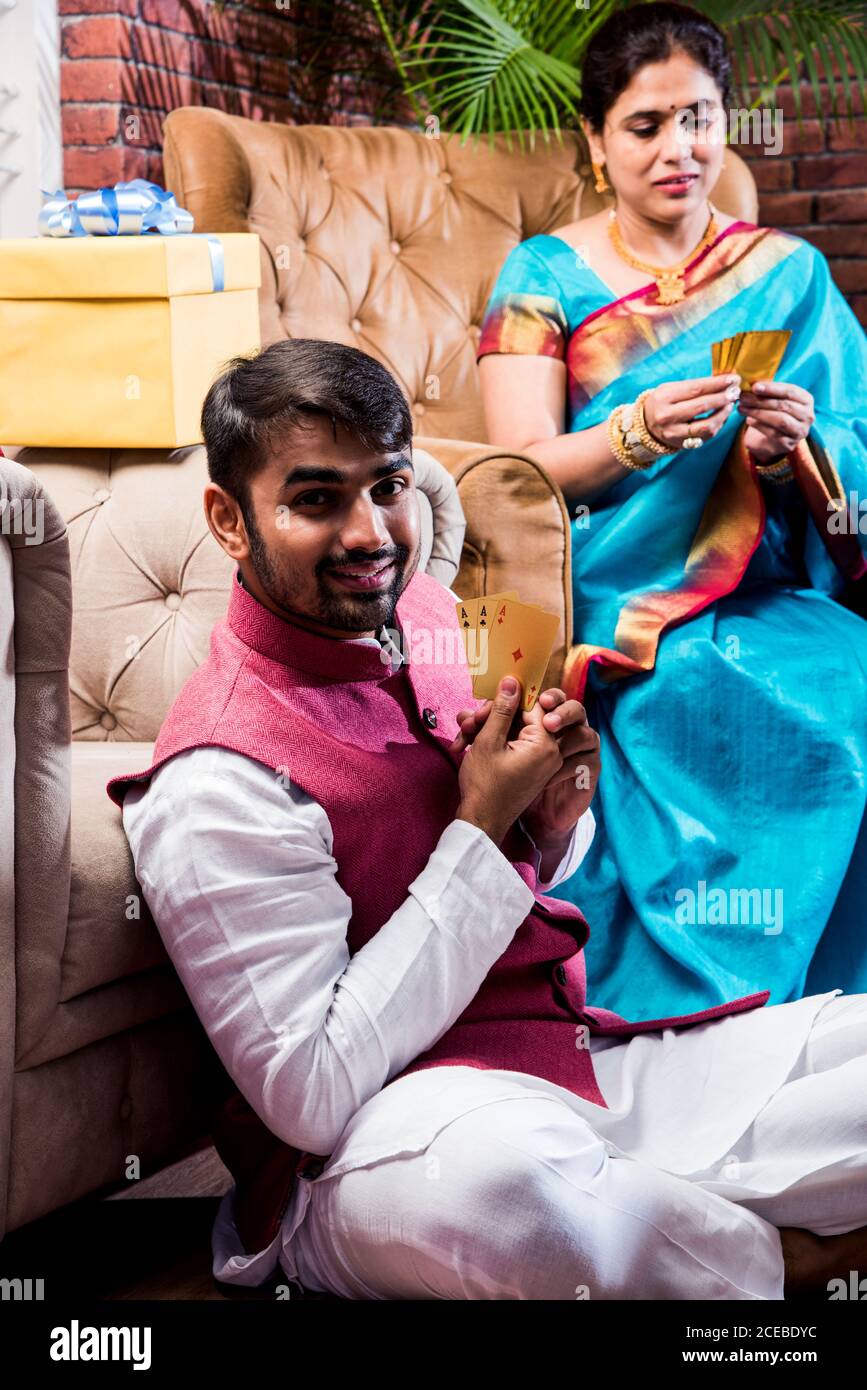 Happy Indian Family giocare teen patti o tre carte gioco la notte del festival di diwali in abiti tradizionali a casa Foto Stock