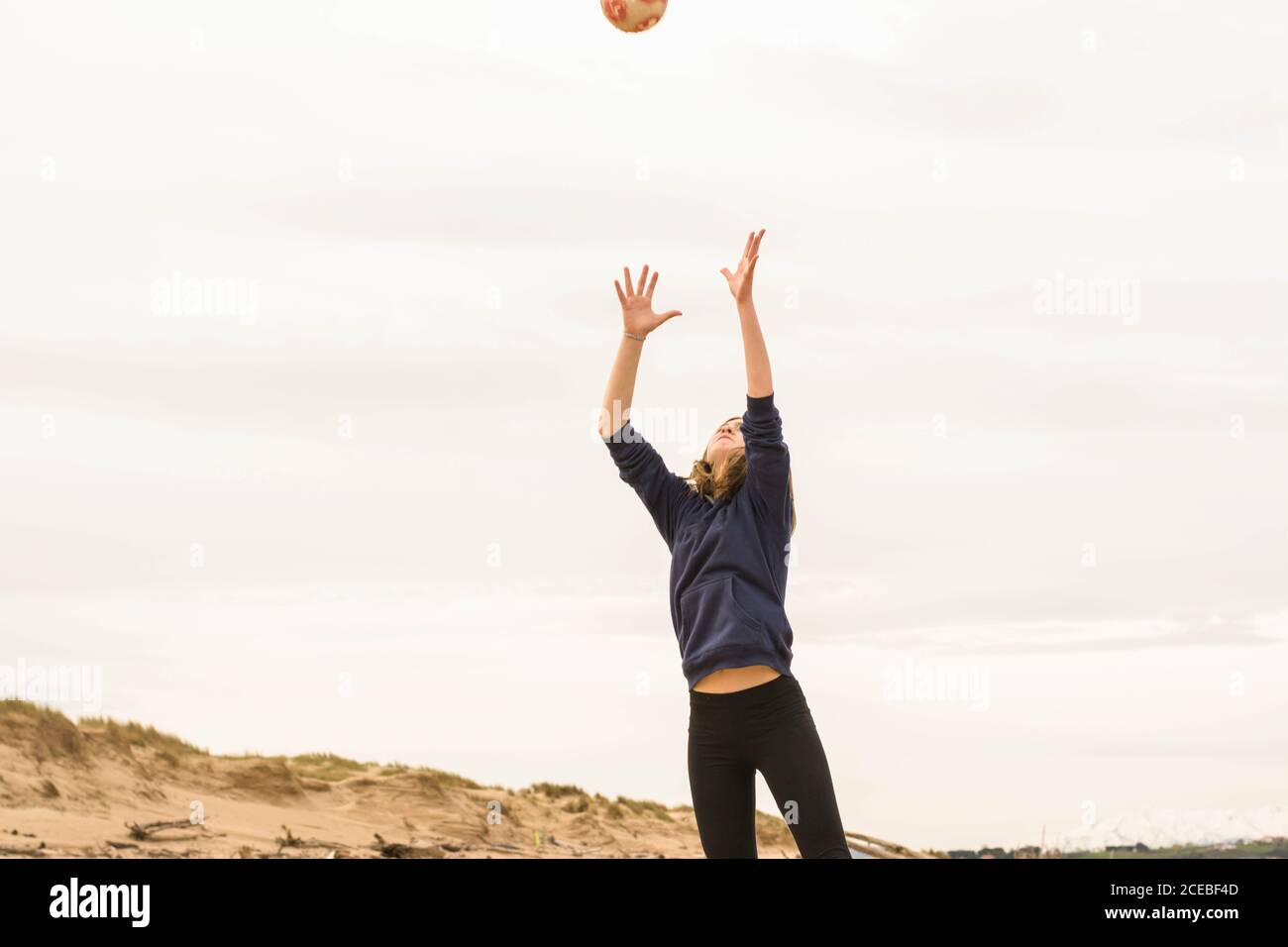 Teenager che gioca con la palla sulla spiaggia Foto Stock