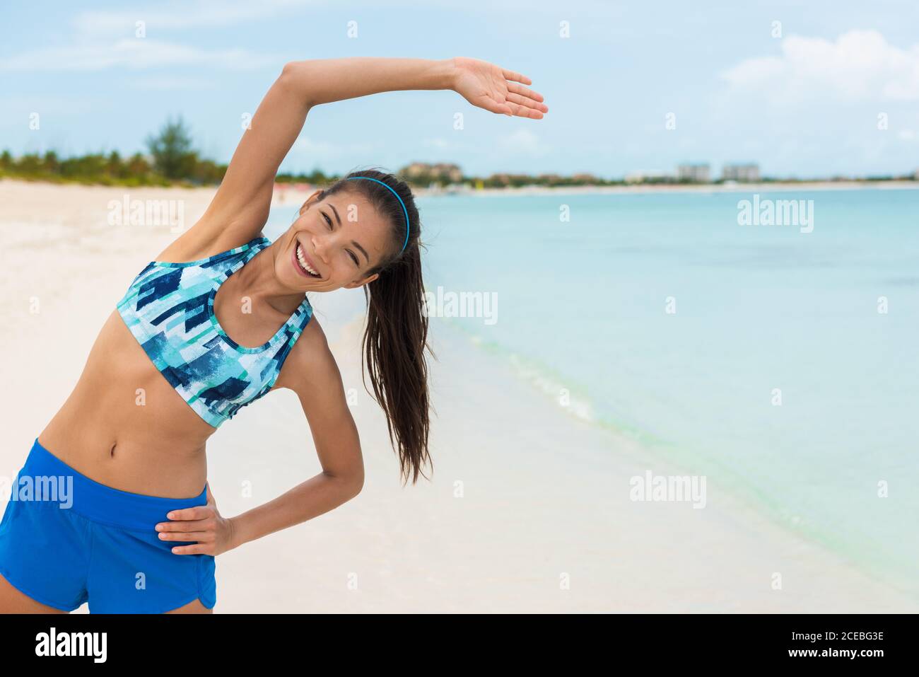 Fitness esercizio donna stretching durante lo yoga o pilates classe sulla  spiaggia. Ragazza asiatica felice che si esercita all'aperto indossando  reggiseno sportivo e pantaloncini, moda Foto stock - Alamy