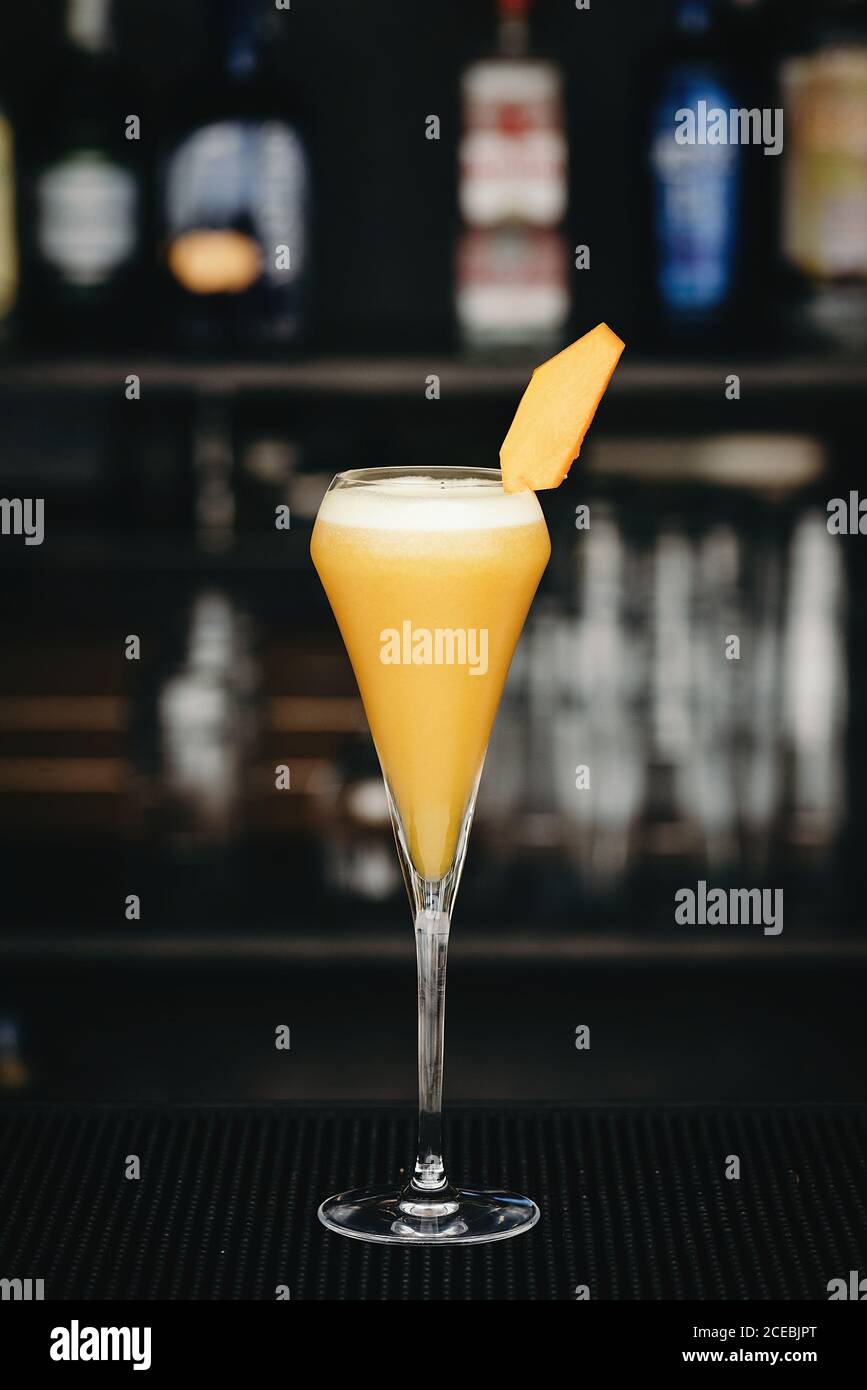 Cocktail alcolico giallo in vetro non comune al bancone del bar. Foto Stock