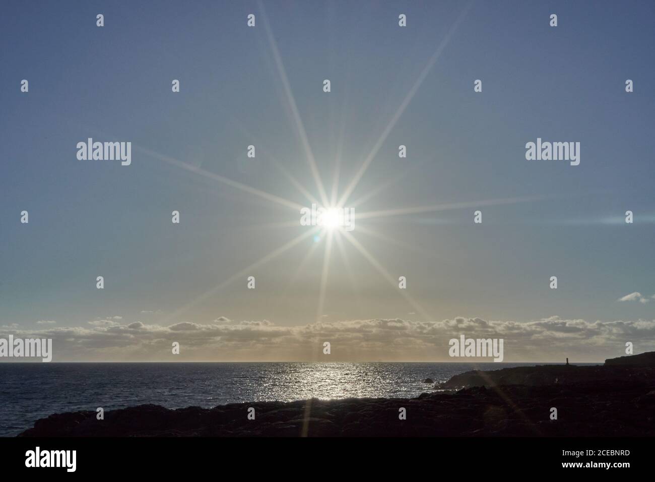 Vista di Bright sole che splende sopra il mare e la costa rocciosa Foto Stock