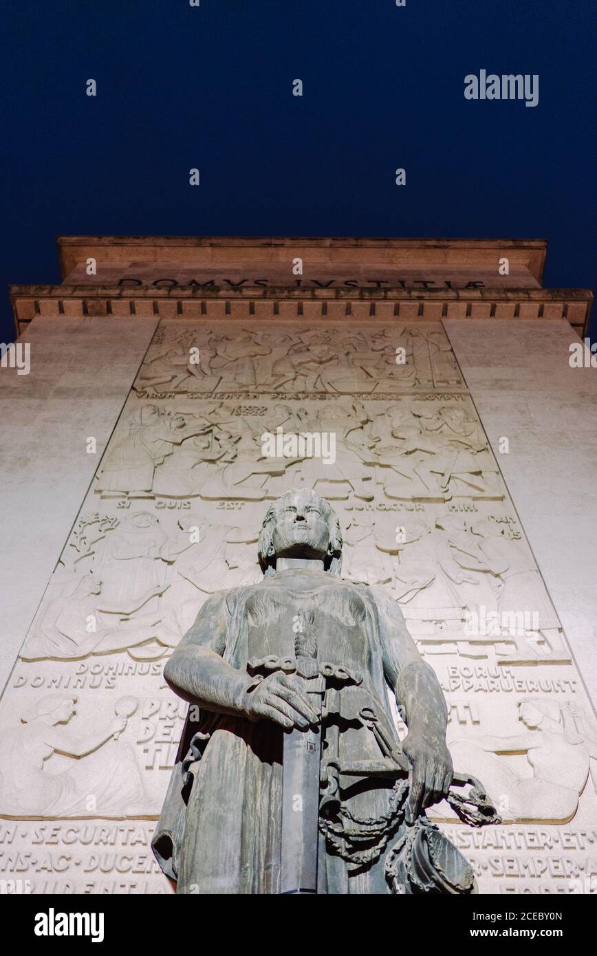 Da sotto grande statua che tiene la spada al muro illuminato. Foto Stock