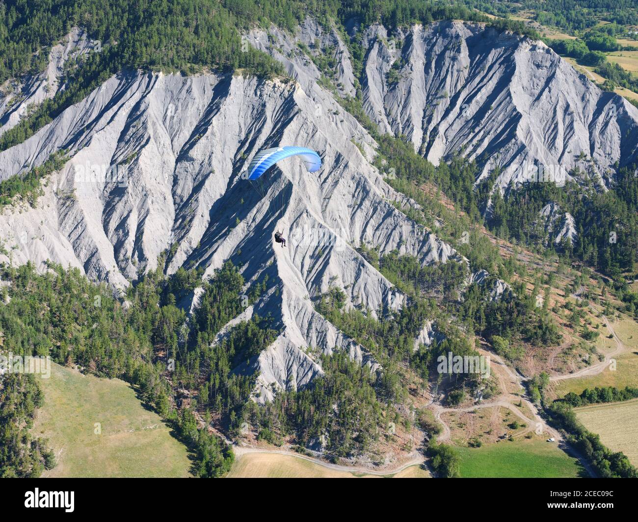 VISTA ARIA-ARIA. Parapendio che sorvola un paesaggio di anfratti erosi. Barcelonnette, Alpi dell'alta Provenza, Francia. Foto Stock