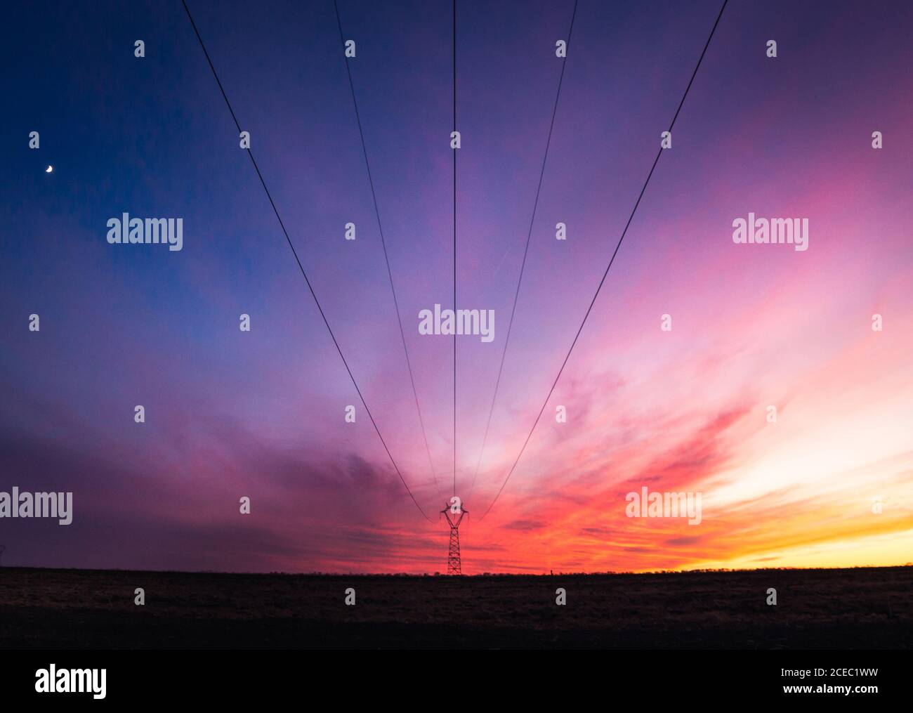 Fili di linea elettrica sotto il cielo multicolore stupefacente dai colori viola scuro ai colori gialli, Spagna Foto Stock