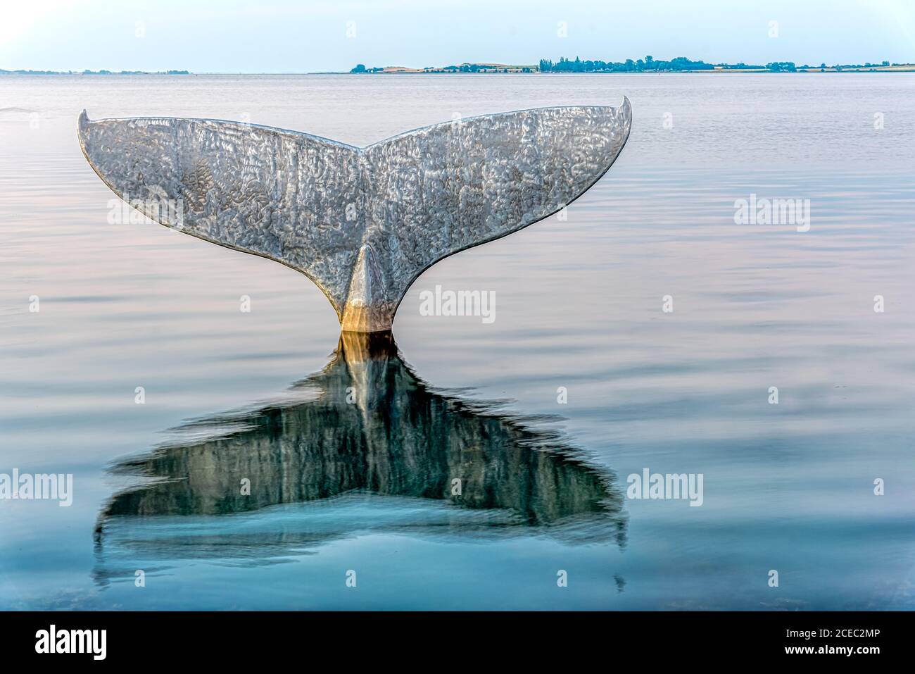 La coda delle balene, una scultura a Faaborg che si riflette in acqua di mare all'ora blu e Avernako sullo sfondo, Faaborg, Danimarca, Augus Foto Stock